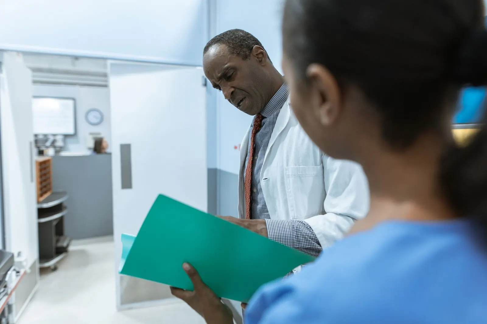 Senior doctor reading through a patient folder held by a nurse